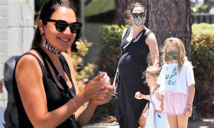 Gal Gadot covers her belly under a figure-hugging black dress while out to lunch with her daughters